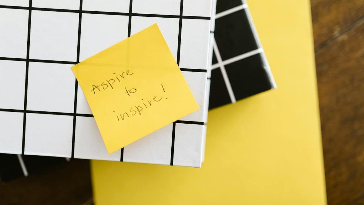 Motivational quote 'Aspire to inspire' on a sticky note placed on books. Minimal and inspirational visual.