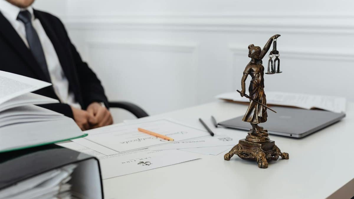 A legal professional's workspace featuring Lady Justice statue, documents, and a laptop.