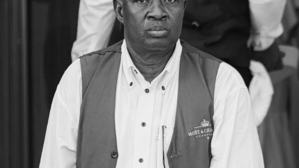 Portrait of a well-dressed black man wearing a vest, captured in black and white, exuding elegance.