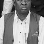 Portrait of a well-dressed black man wearing a vest, captured in black and white, exuding elegance.
