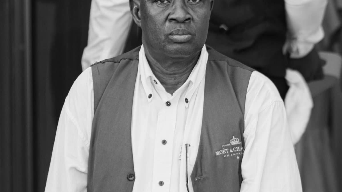 Portrait of a well-dressed black man wearing a vest, captured in black and white, exuding elegance.