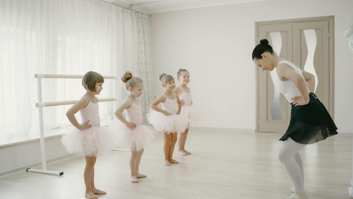 A group of young ballerinas learning ballet with their instructor in a bright studio.
