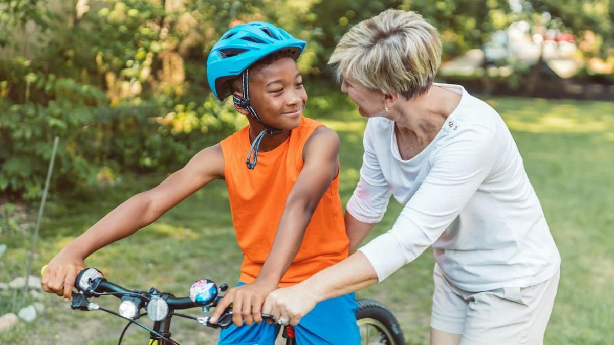 A joyful moment between a mother and son learning to ride a bike in a sunny park.