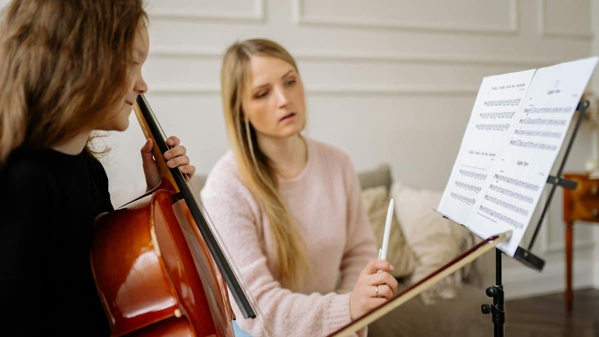 A music lesson featuring a child learning to play the cello, guided by a female teacher.