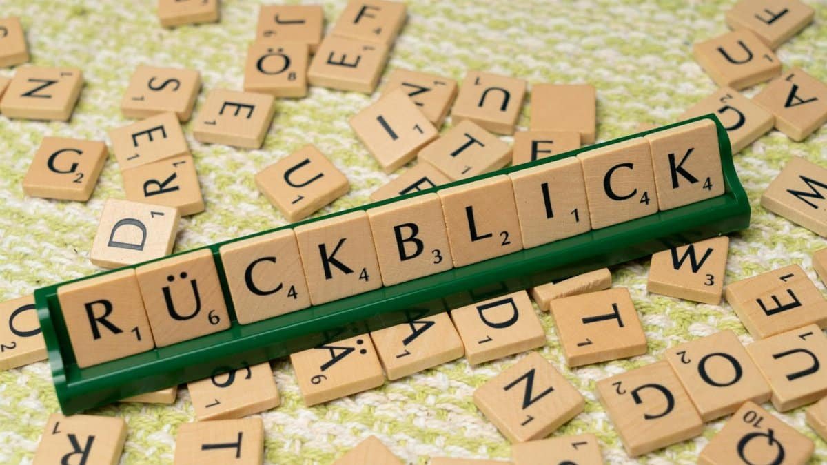 Wooden Scrabble tiles arranged to spell 'Rückblick' on a textured surface, showcasing language and typography.
