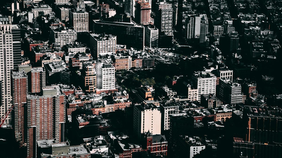 A dramatic aerial view of New York City's bustling downtown skyline captured in daylight.