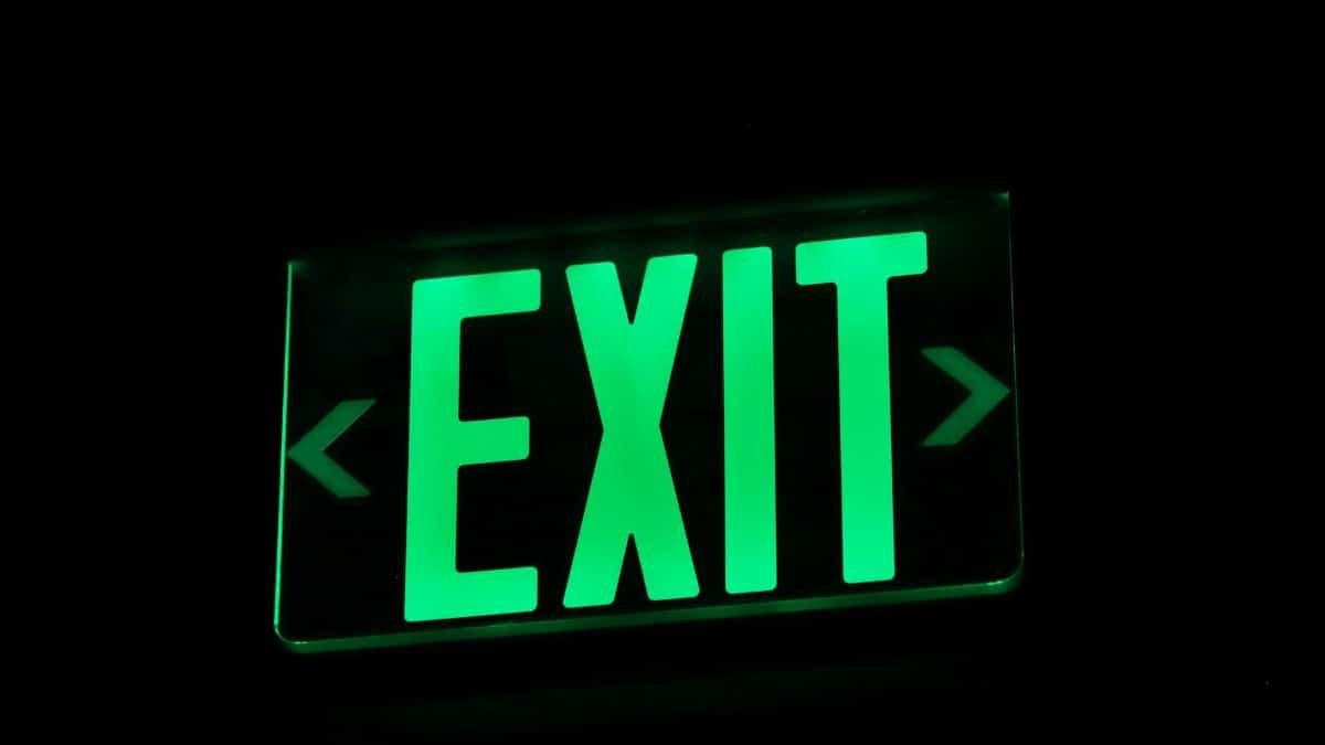 Bright green exit sign illuminated in darkness, indicating direction.