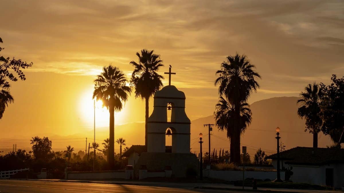 Scenic silhouette of a bell tower surrounded by palm trees during sunset in Redlands, California.