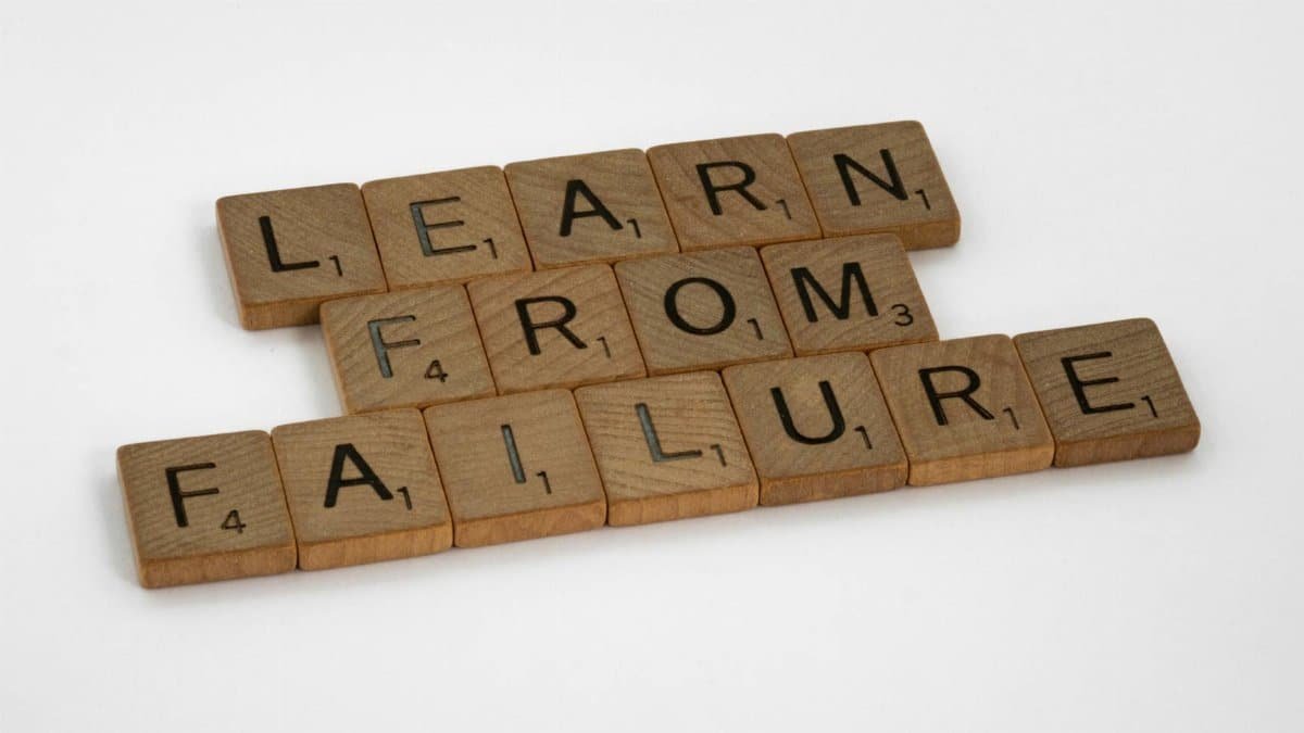 Wooden Scrabble tiles spelling 'Learn from Failure' on a white background, promoting resilience.