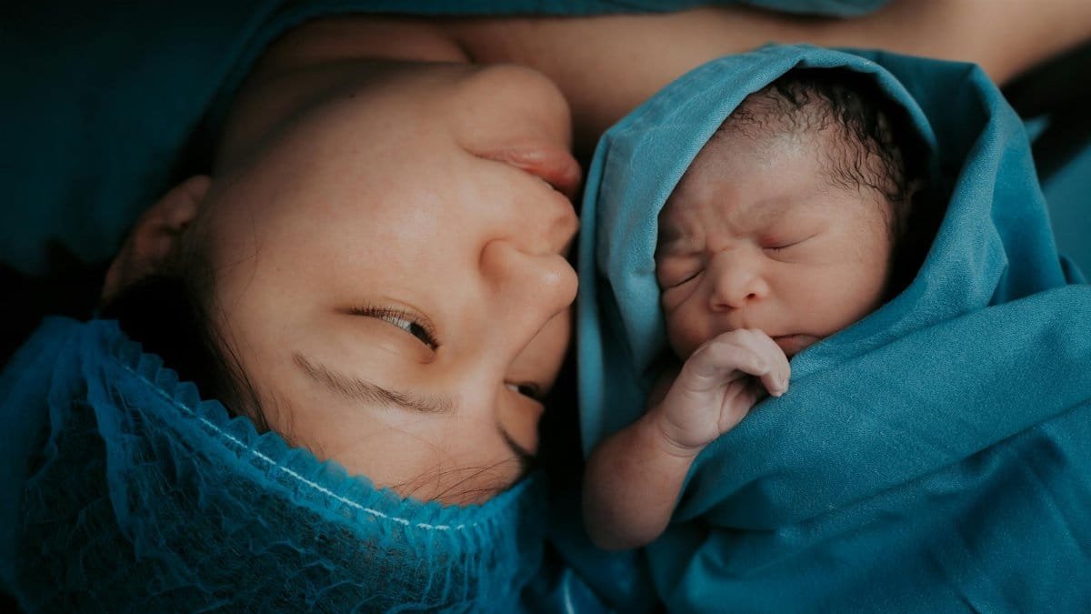 A touching image of a mother and her newborn baby wrapped in blue medical blankets.