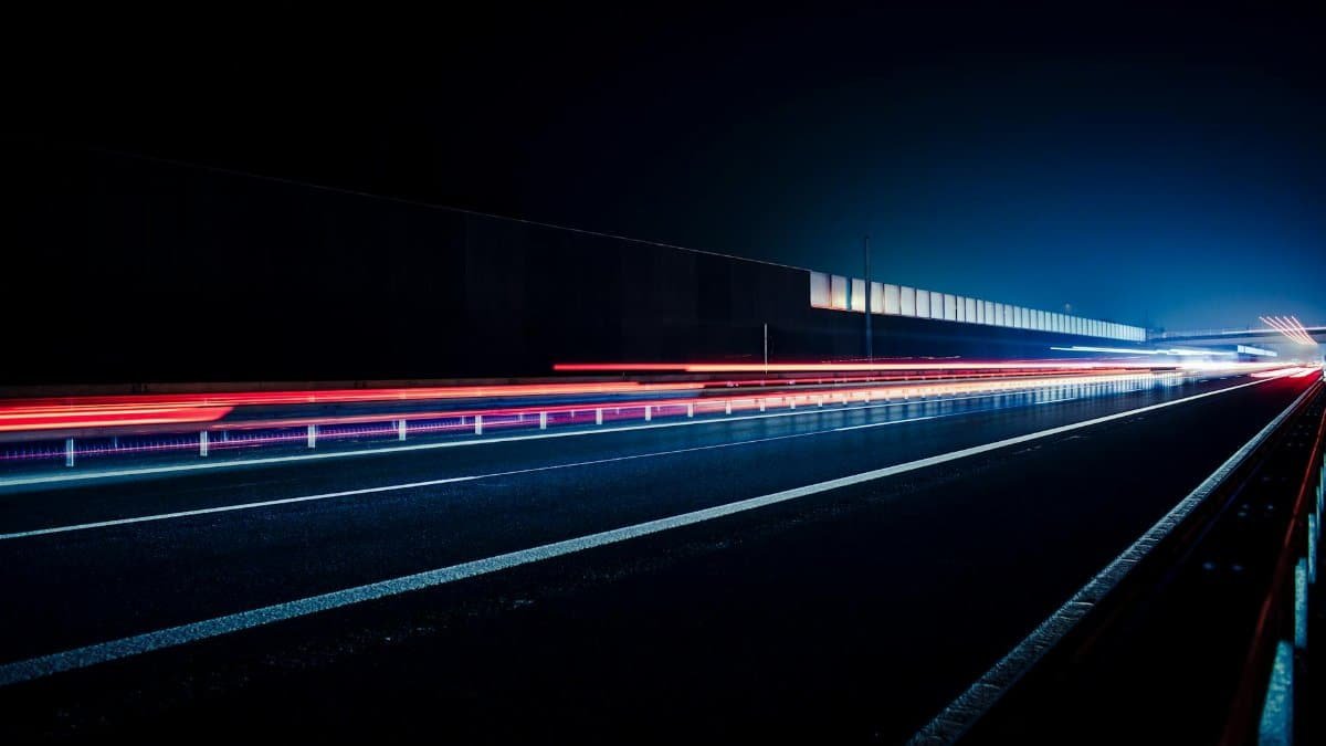 Vibrant long exposure photo capturing light streaks on a highway at night, illustrating speed and motion.