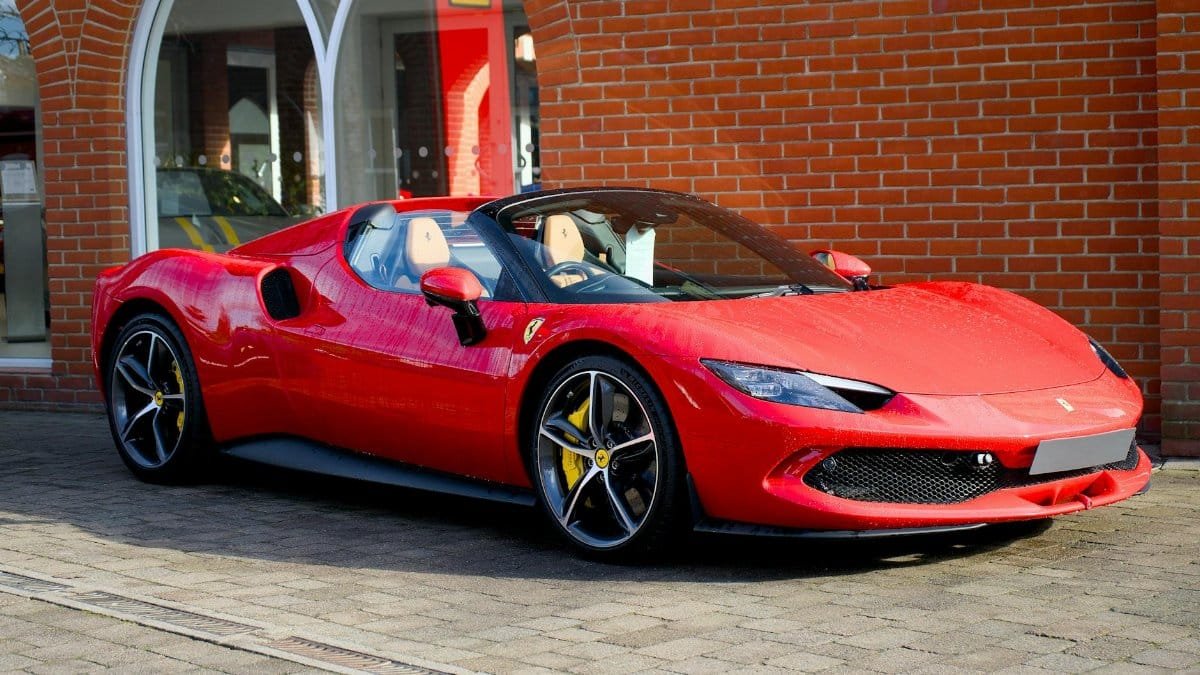 Sleek red Ferrari sports car parked outdoors with brick façade background.