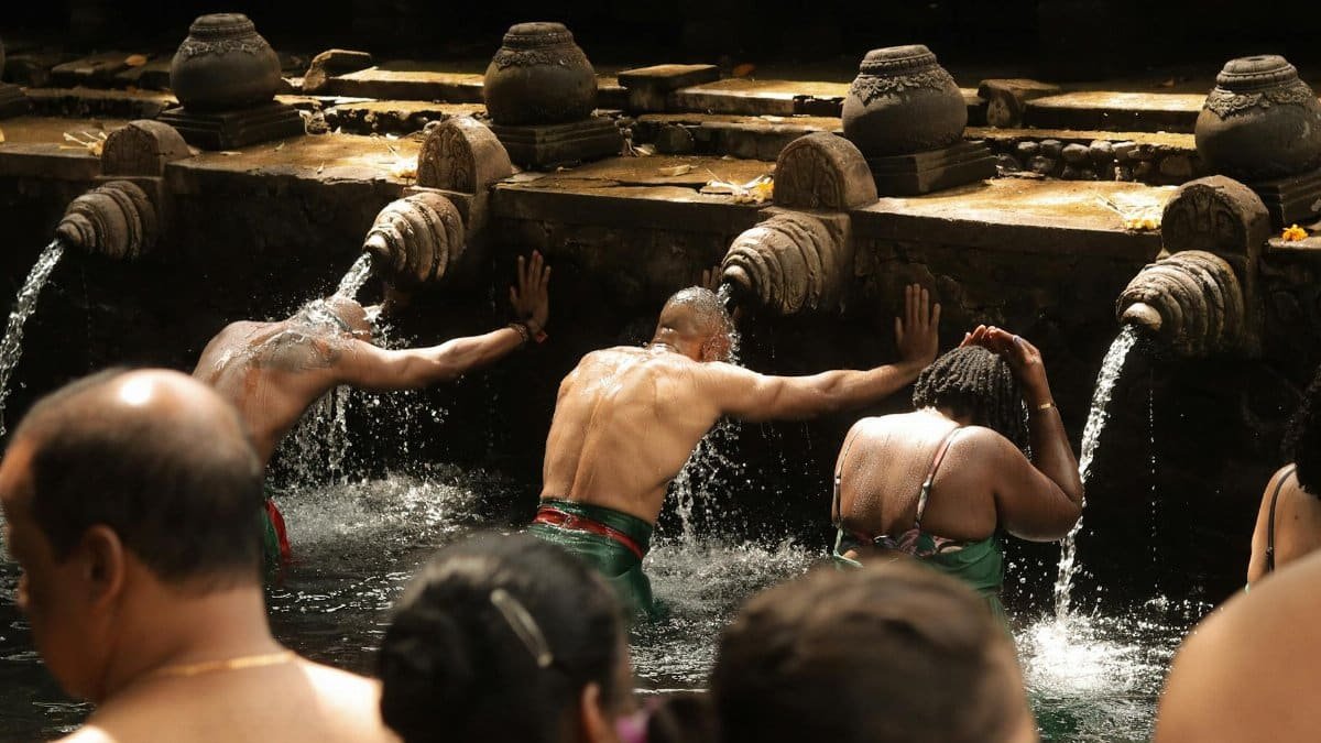 People engage in a traditional water purification ritual at a sacred site, symbolizing spiritual cleansing.