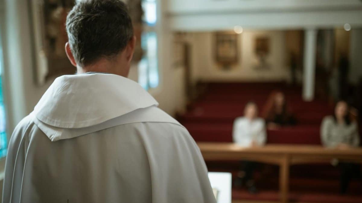 A priest seen from behind delivering a sermon in a church, focusing on spirituality and faith.