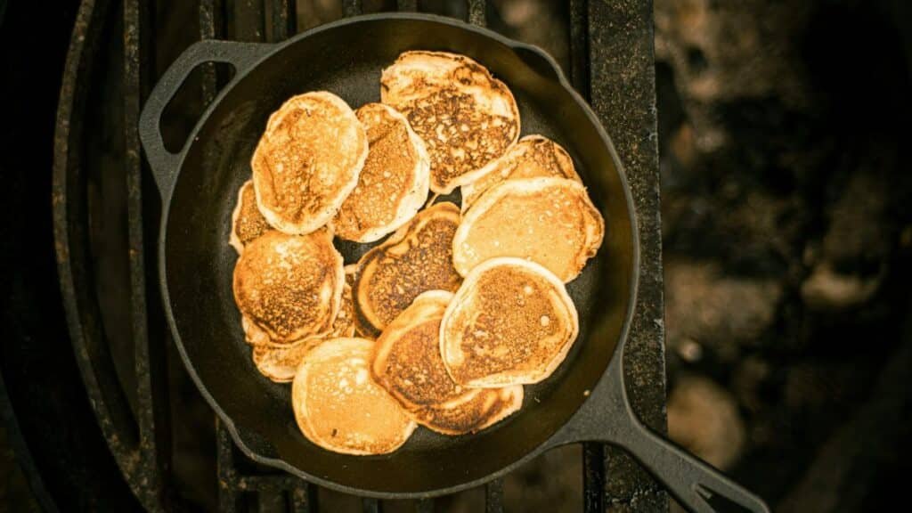 A delicious stack of golden pancakes cooked in a cast iron skillet, photographed from above.