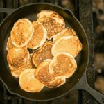 A delicious stack of golden pancakes cooked in a cast iron skillet, photographed from above.