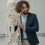 A biology teacher demonstrates the human skeleton model in an engaging classroom setting.