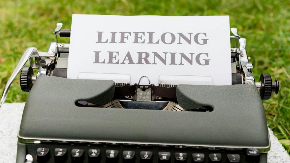 Close-up of a typewriter typing 'Lifelong Learning' outdoors, symbolizing continuous knowledge growth.