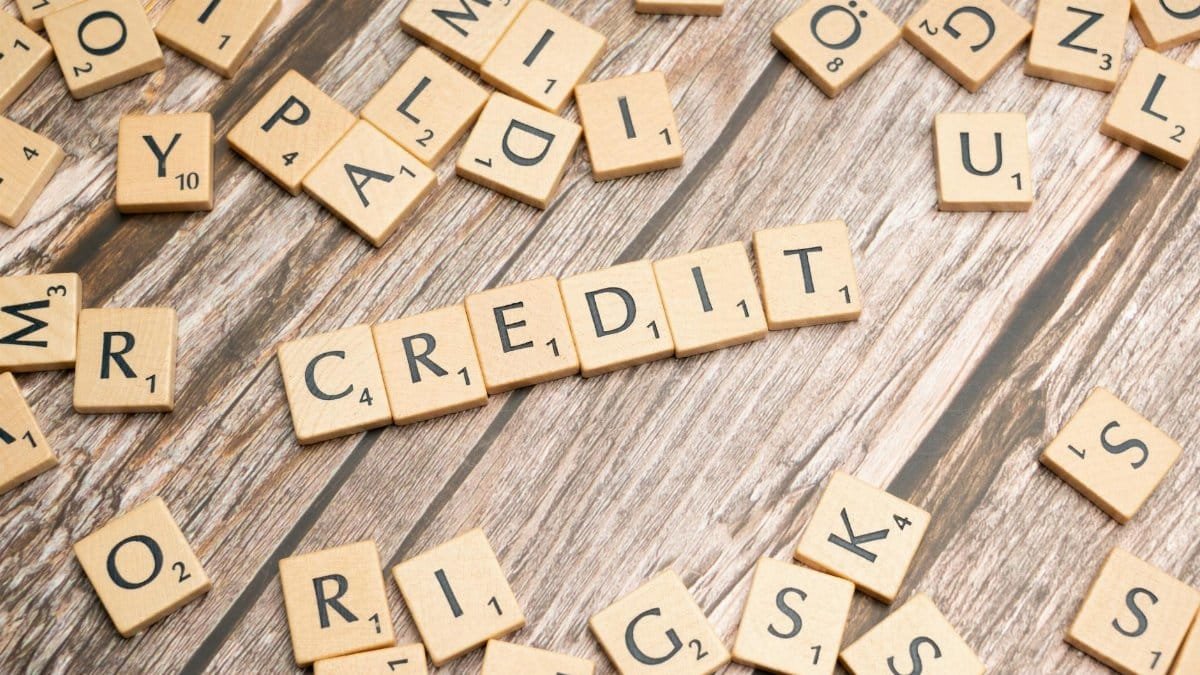 Wooden letter tiles arranged to spell 'CREDIT' on a rustic table background.