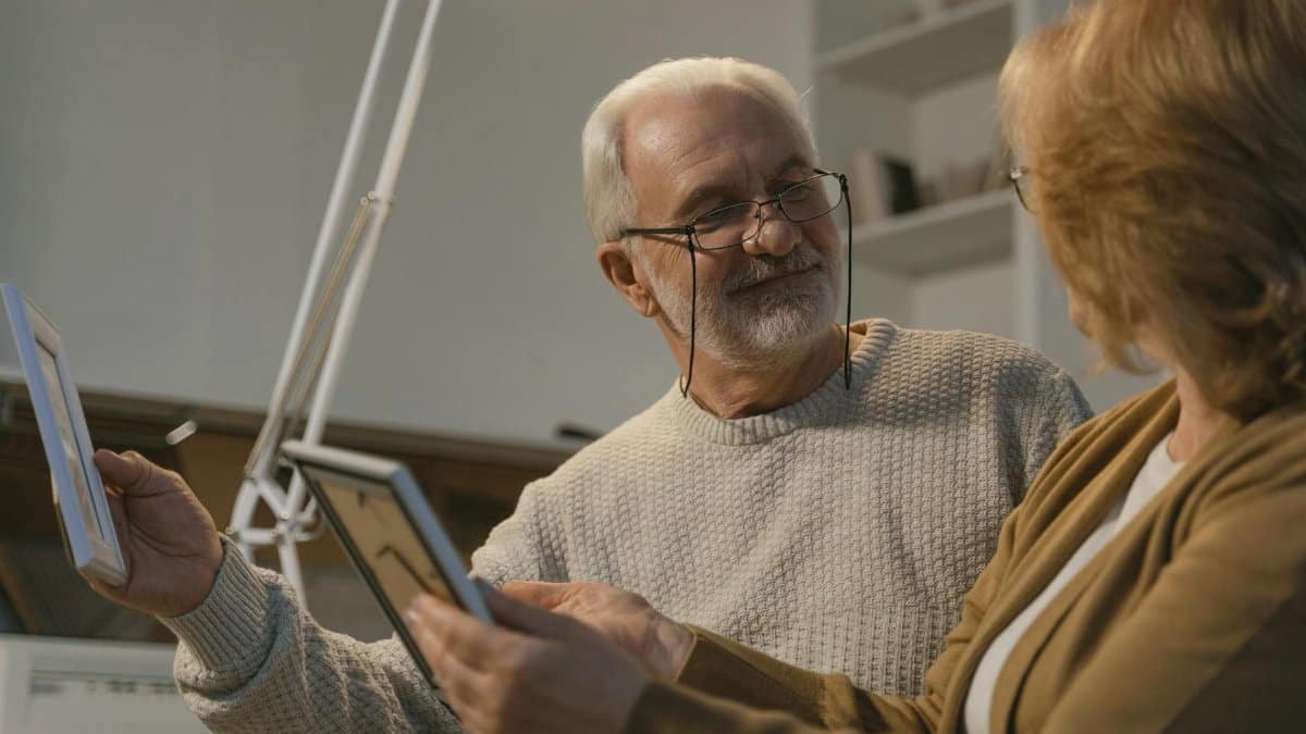 Senior couple sharing memories with photo frames in a cozy home setting.