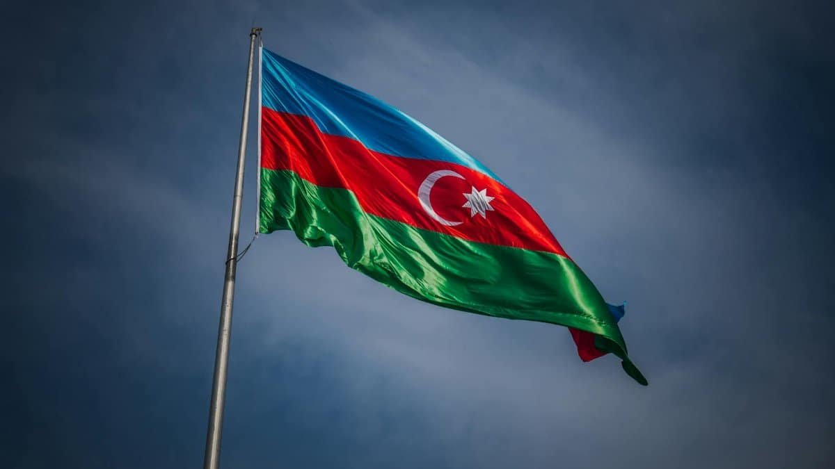 A vibrant Azerbaijan flag waves proudly against a clear blue sky in Baku, symbolizing national pride.