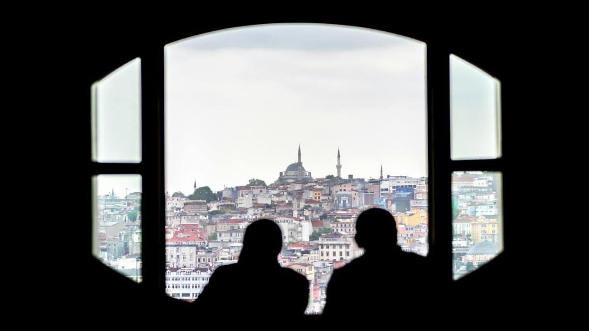 Two silhouettes viewing the Istanbul cityscape through a window, highlighting the distinctive skyline.