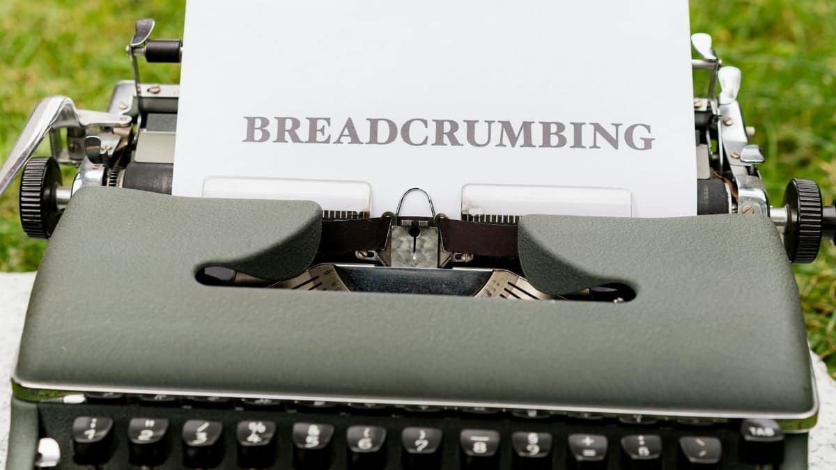 Close-up of a vintage typewriter outdoors with paper reading 'BREADCRUMBING'.