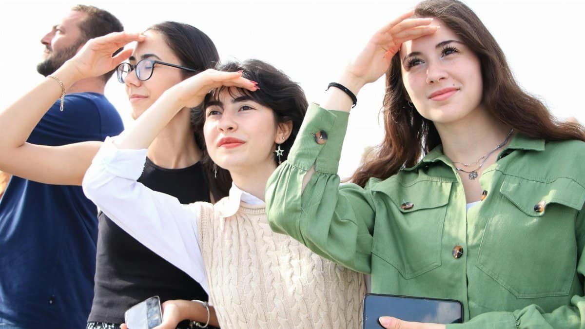 Group of young adults shielding eyes and looking into the distance on a sunny day.