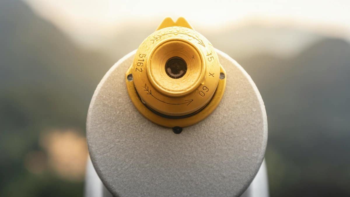 A close-up of a coin-operated telescope with a scenic blurred background.
