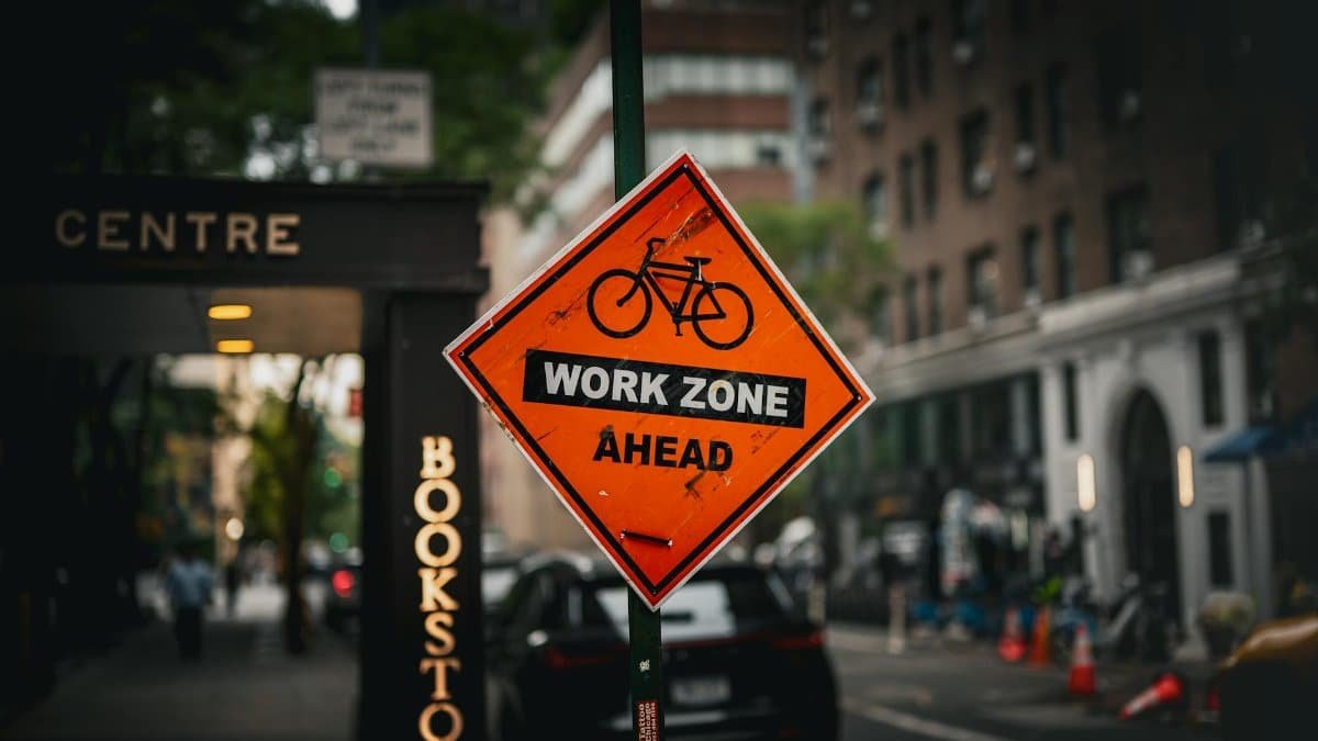 A bicycle work zone sign in a busy New York City street scene.