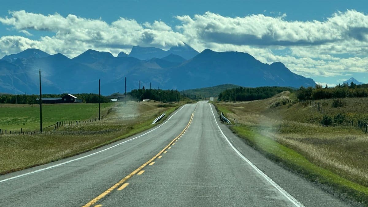 Expansive straight road leading to majestic mountains under clear skies. Perfect for travel themes.