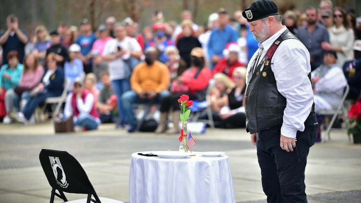 A veteran stands solemnly at a memorial ceremony honoring fallen soldiers at Fort Bragg, NC.