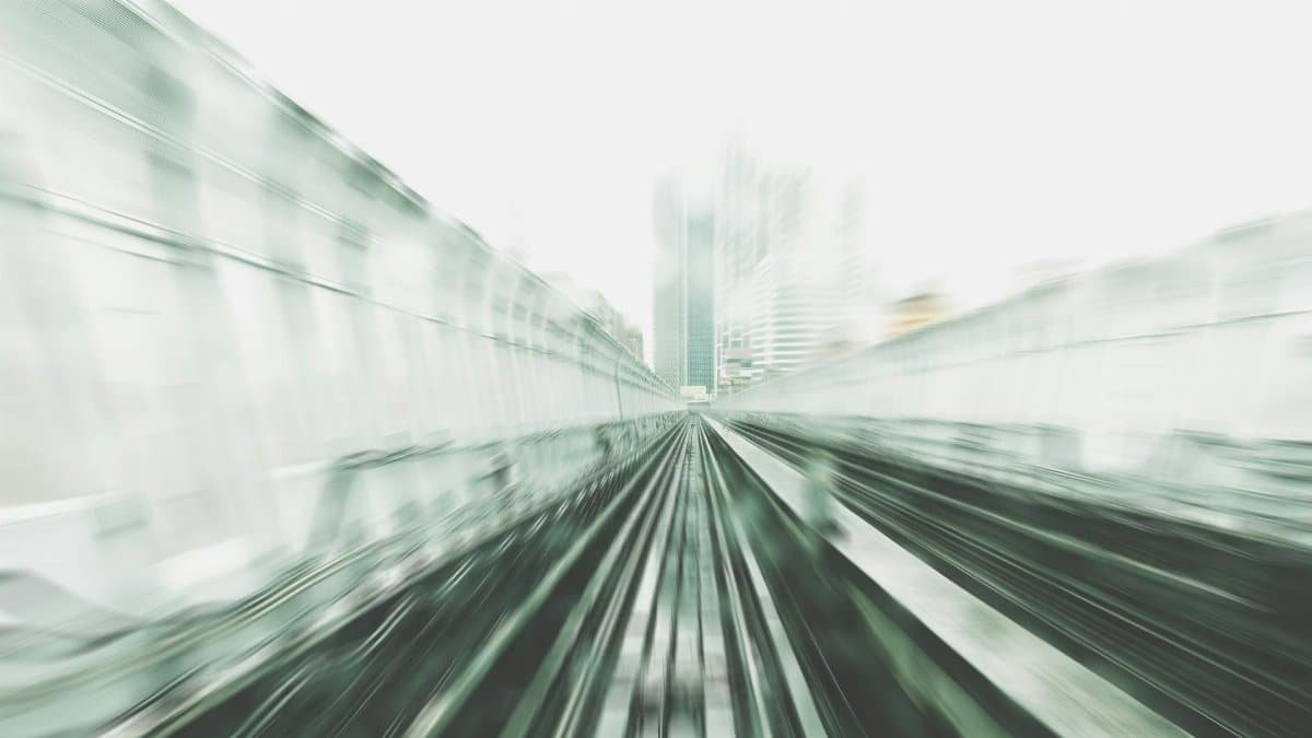 Abstract motion blur view of urban train tracks in a city setting, indicating speed and movement.