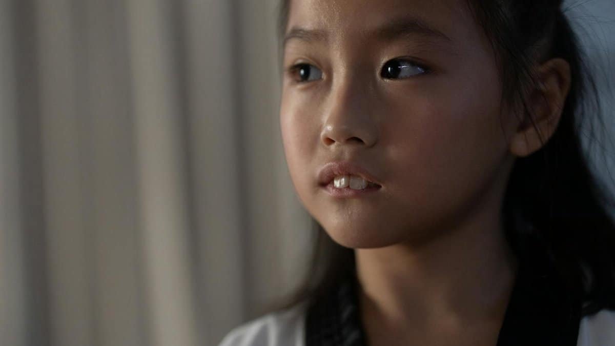 Close-up portrait of a young girl in a martial arts uniform, looking thoughtful.