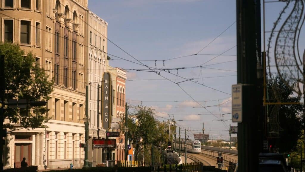Street scene in downtown Houston featuring historic buildings and a train under a clear blue sky.
