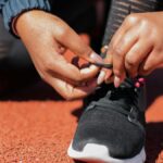 Close-up of athlete tying laces on sneakers on a running track, emphasizing readiness.