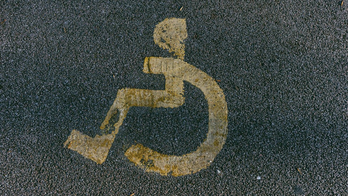 Close-up view of a weathered wheelchair symbol on asphalt, indicating disability access.