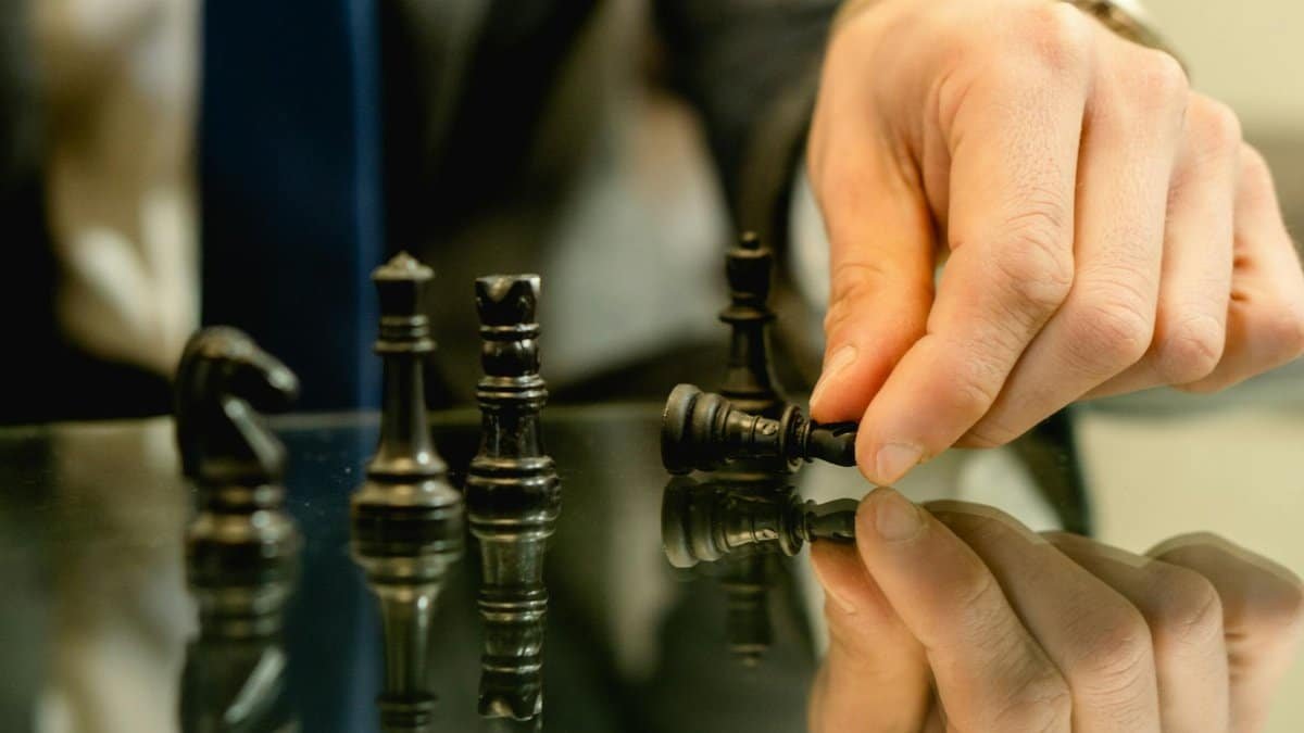 Hand moves chess piece in strategic game setting, reflecting planning and decision-making.