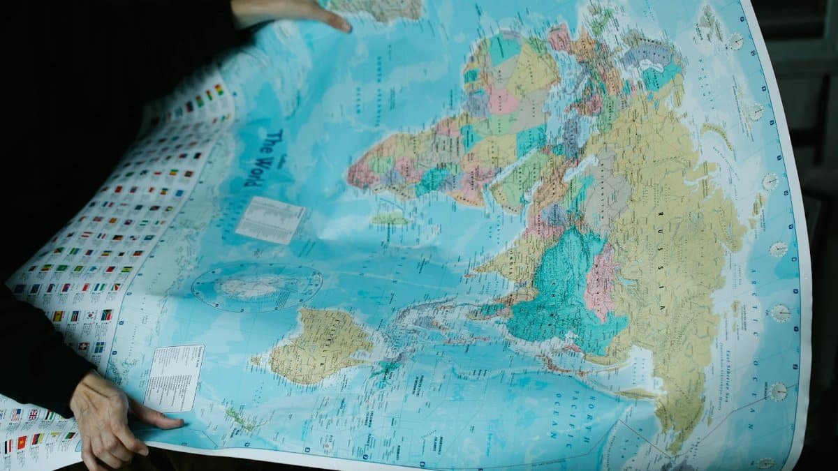 A person is holding a detailed political world map with vibrant colors.