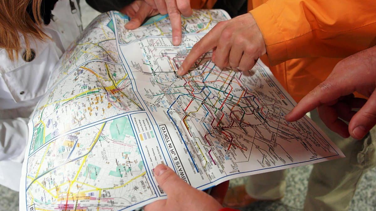 Group of people pointing at a Tokyo subway map, planning their route in Japan's capital city.