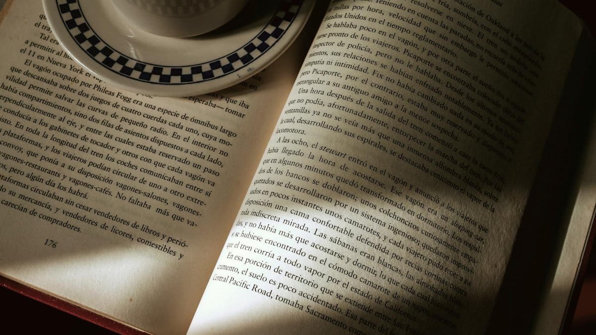 An open book with a coffee cup, capturing a serene reading atmosphere indoors.