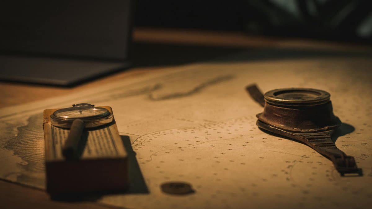 A vintage compass and magnifying glass on an old nautical map evoke a sense of adventure and discovery.