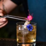 A bartender adds floral garnish to a cocktail in a trendy New York bar.