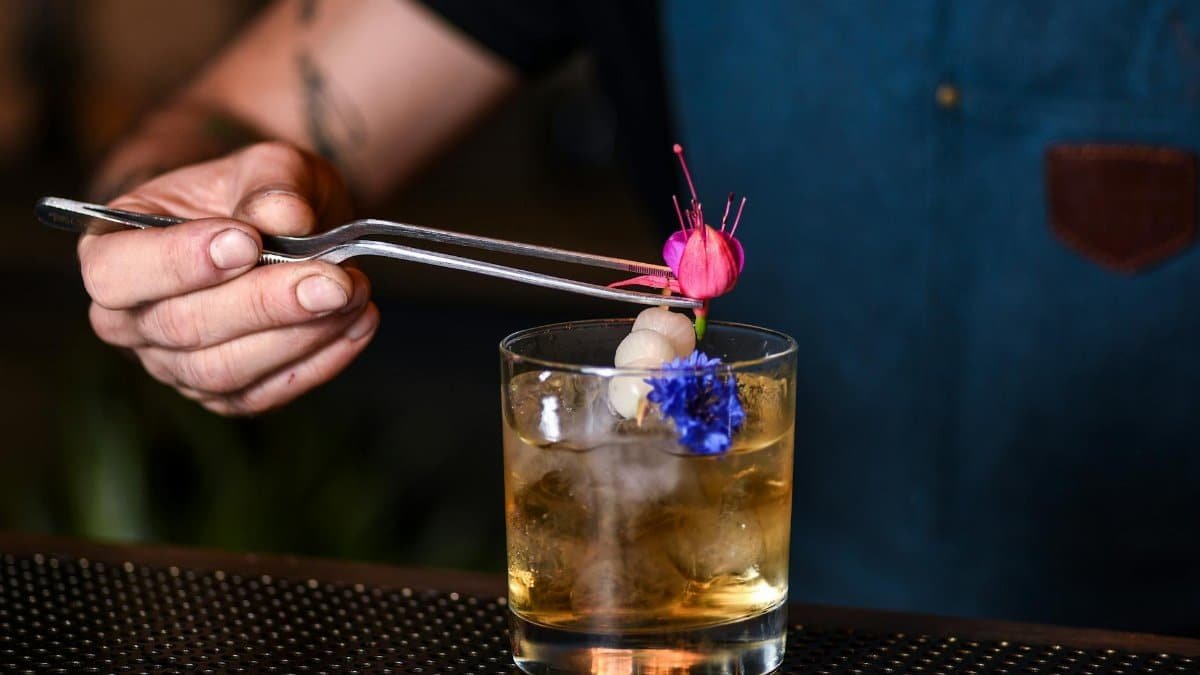 A bartender adds floral garnish to a cocktail in a trendy New York bar.