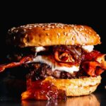 Close-up of a gourmet burger featuring bacon and sauce in vivid detail.