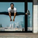 Man performing a split jump on concrete, showcasing fitness and agility.