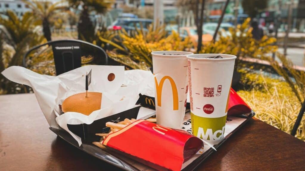 An appetizing fast food meal with burger, french fries, and drinks on an outdoor table in urban setting.