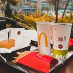 An appetizing fast food meal with burger, french fries, and drinks on an outdoor table in urban setting.