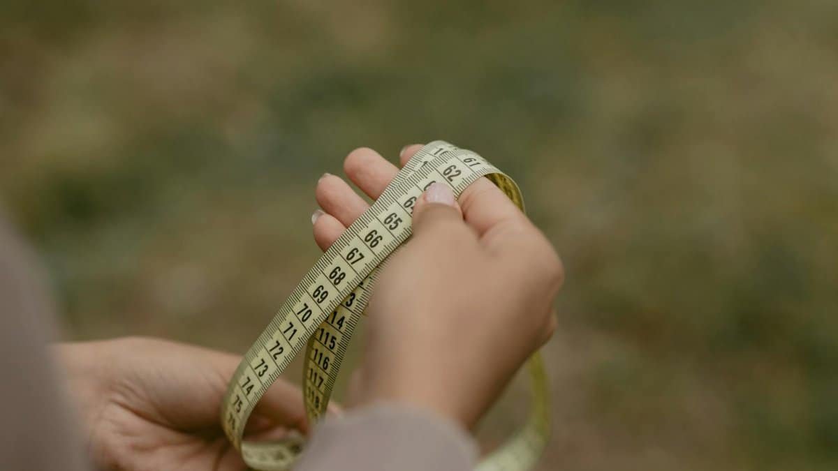 Hands holding a rolled measuring tape, focused on numbers and markings.