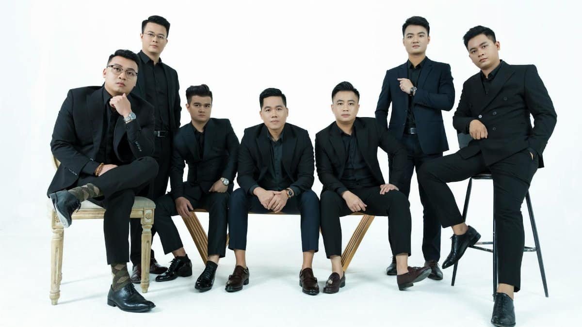 A stylish group of men in suits posing elegantly against a white backdrop in a studio setting.